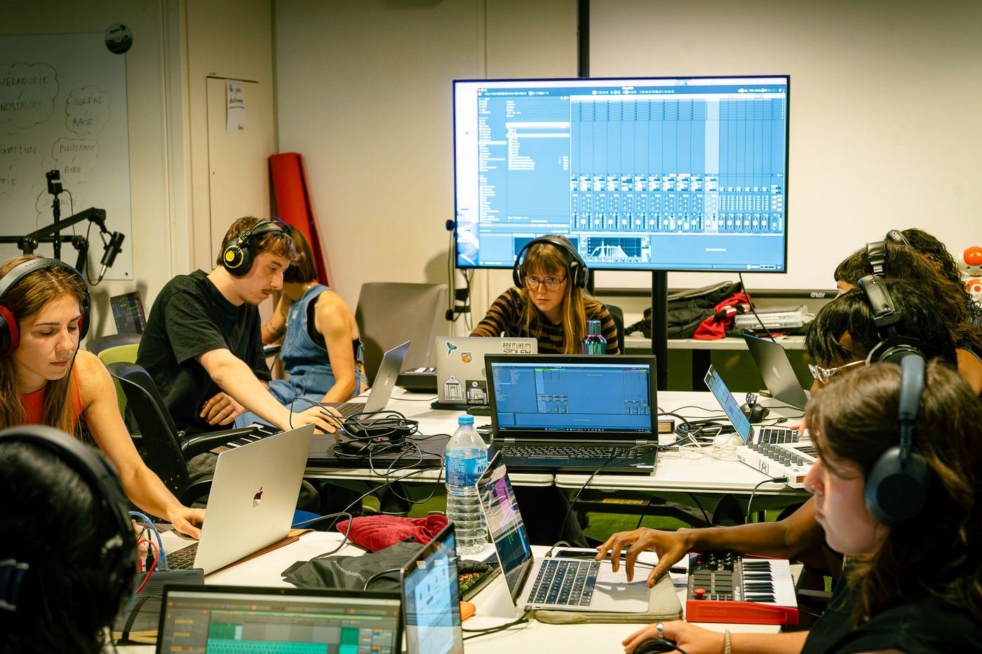 Participantes concentrées, un projet de musique affiché sur le grand écran